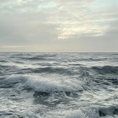 Fototapeta premium Tranquil ocean waves under a cloudy sky, showcasing the serene beauty of nature's vast seascape in soft morning light.
