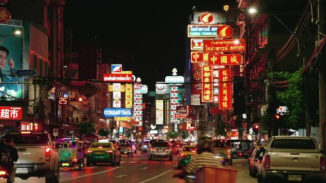 Time-lapse of Yaowarat Road in Chinatown at night. Bright neon signs and flow of cars and people. Tourists walking by night market for try street food. Bangkok, Thailand