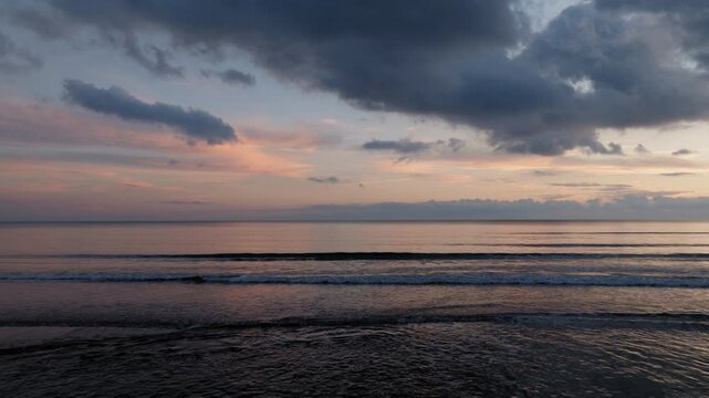 Aerial: Flying low over the calm sea during a beautiful sunset in Letrina beach, Elis province, Greece