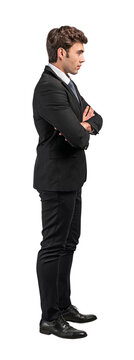 Businessman in a suit standing sideways with arms crossed, isolated on a white background. Professional attire and confident pose