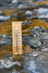 Wooden thermometer showing sub-zero temperature in celsius and fahrenheit scale, stuck in frozen...