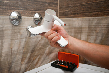 Professional plumber working carefully, installing or repairing bathtub faucet in modern bathroom