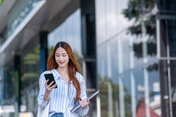 Woman is walking down the street with a cell phone in her hand