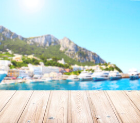 Plakat Sunny Capri island sea view and wood terrace flooring. Blank wooden table top on seascape background. Summer vacation, relaxing on beach, travel, trip abroad on vacation, cruises and tours concept