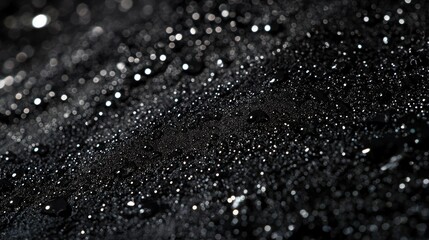 Macro shot of water droplets on a black textured surface, capturing the elegance and intricacy of water patterns on dark backgrounds