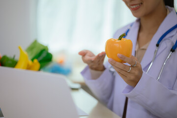 A dietitian or nutrition specialist in a doctor's office, wearing a lab coat, provides attentive...