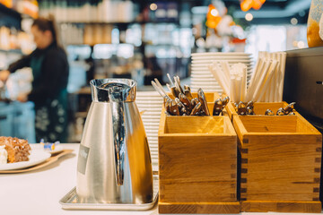 Stainless Steel Pot and Wooden Cutlery Holders on a Cafe Counter