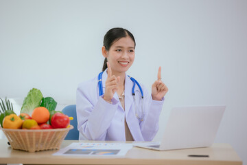 A female nutritionist holds a stethoscope to examine her health. She smiles and promotes healthy...
