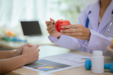 A female nutritionist holds a stethoscope to examine her health. She smiles and promotes healthy...