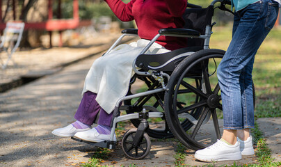 Obraz premium Nursing home. Young caregiver helping senior woman in wheelchair.