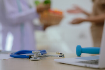 Female doctor or nutritionist sitting at table with fresh fruits and vegetables to promote healthy eating and living, nutrition and weight control.