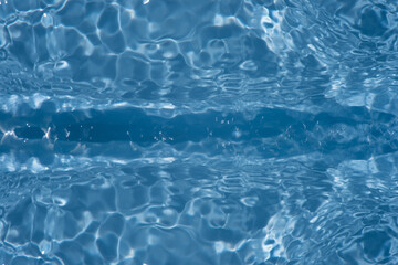 Blue water with ripples on the surface. Defocus blurred transparent blue colored clear calm water surface texture with splashes and bubbles. Water waves with shining pattern texture background.