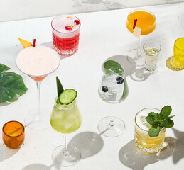 Assorted alcoholic cocktails on white background with sunlight shadows. Summer cocktails menu....