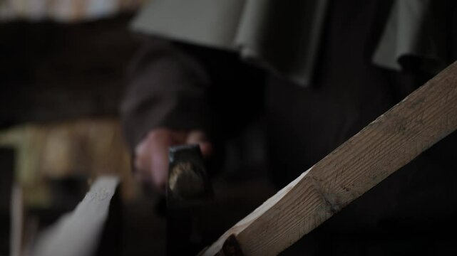 Master Craftsman Carves Wood with Adze, Splinters Falling in Rustic Workshop of Traditional Artistry
