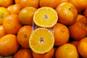Close-up of freshly harvested oranges, showcasing a vibrant display of whole fruits and a halved orange revealing juicy, succulent segments, symbolizing freshness, health, and natural sweetness