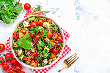 Quinoa salad with tomatoes, paprika, avocado, cucumbers and parsley. White table background, top view