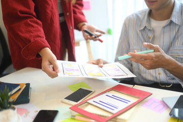 UX designers analyzing colorful charts and app interface wireframes during brainstorming