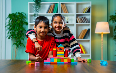 Indian Kids Building Structures with Colorful Wooden Blocks and Playing Joyfully at Home