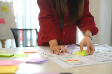 Team of creatives collaborating on a UX UI project at workspace filled with flowcharts and digital prototypes