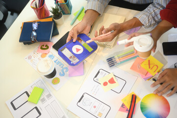 UX designers analyzing colorful charts and app interface wireframes during brainstorming