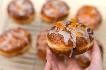 Apetyczne drożdżowe pączki pięknie zdobione lukrem z cukru pudru i skórką pomarańczową, tradycyjne przepisy, tłusty Czwartek 