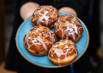 Tradycyjne polskie pączki nadziewane różą polane słodkim lukrem z kandyzowaną skórką pomarańczową 