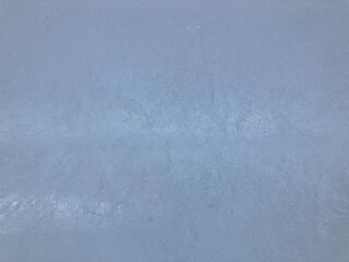 Close-up of an ice wall with small cracks. Outdoors in winter. It's frozen. Light is shining through it.