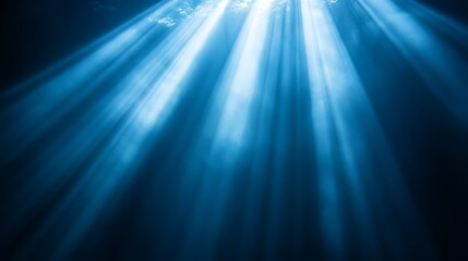 Underwater sunbeams, ocean depth, light rays, dark blue background, nature scene.