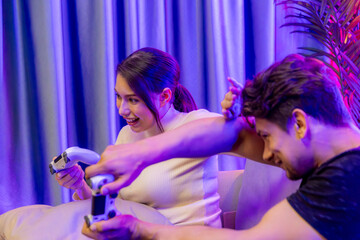 Couple joyful funny players playing video game on TV using joysticks, fighting winner trying to...