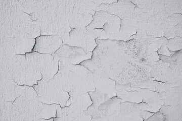A close-up view of peeling white paint on an aged wall highlighting texture and wear over time