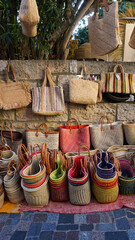Display of colorful handmade straw woven bags and baskets for sale at the market in Le Lavandou,...