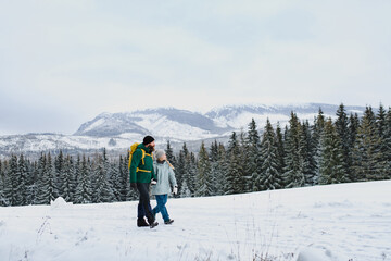 Dad and girl in the middle of snowy nature. Hiking in winter mountains. Winter family walk.