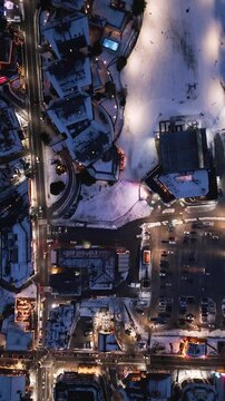 Evening aerial view of a snowy town illuminated by colorful lights during winter festivities. Bansko, Bulgaria