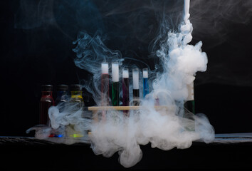Chemistry glassware test tubes measuring jugs with colourful liquids and swirling smoke