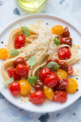 Linguine with roasted cherry tomatoes, grated cheese and basil, vertical shot, selective focus, middle close-up