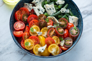 Bowl of salad with cherry tomatoes, green beans and blue cheese, horizontal shot, middle closeup
