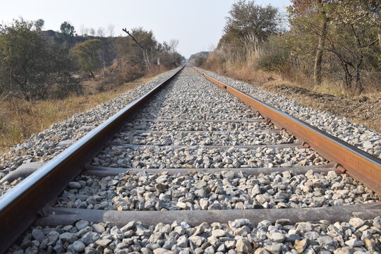 Here A single-track railway line captured symmetrically, offering a calm, ordered perspective into the horizon. This minimalist scene emphasizes clarity, direction, Pair of empty train tracks