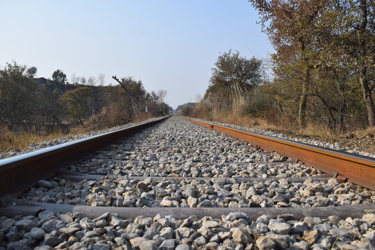 Here A single-track railway line captured symmetrically, offering a calm, ordered perspective into the horizon. This minimalist scene emphasizes clarity, direction, Pair of empty train tracks