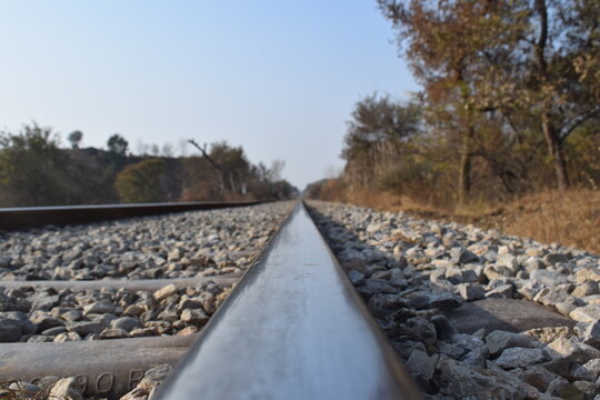 Here A single-track railway line captured symmetrically, offering a calm, ordered perspective into the horizon. This minimalist scene emphasizes clarity, direction, Pair of empty train tracks