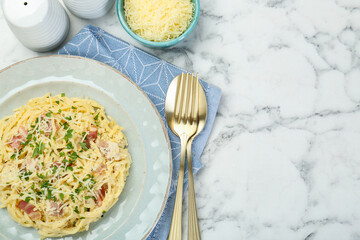 Delicious pasta Carbonara with bacon served on white marble table, flat lay. Space for text
