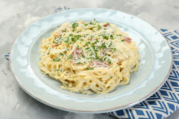 Delicious pasta Carbonara with bacon on gray textured table, closeup