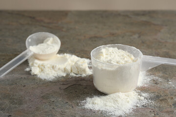Protein powder and scoops on grey textured table
