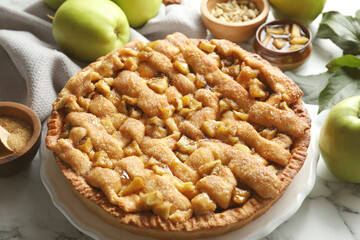 Homemade apple pie and ingredients on white marble table