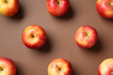 Ripe red apples on brown background, flat lay