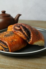 Tasty buns with poppy seeds on wooden table, closeup