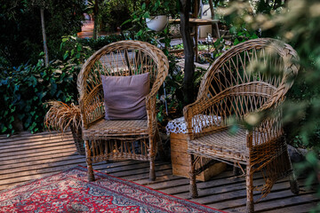 Obraz premium Cozy outdoor seating area with wicker chairs and greenery in a tranquil garden setting