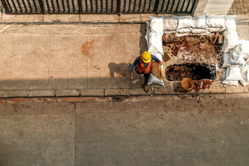 Asian adult male construction worker doing pedestrian walkway excavation work manually at noon