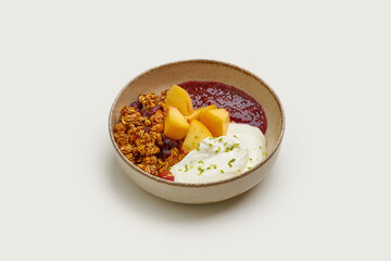 A bowl of homemade granola topped with fresh fruit, yogurt, and a drizzle of sweet jam.