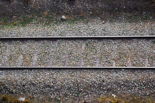 Here A single-track railway line captured symmetrically, offering a calm, ordered perspective into the horizon. This minimalist scene emphasizes clarity, direction, Pair of empty train tracks