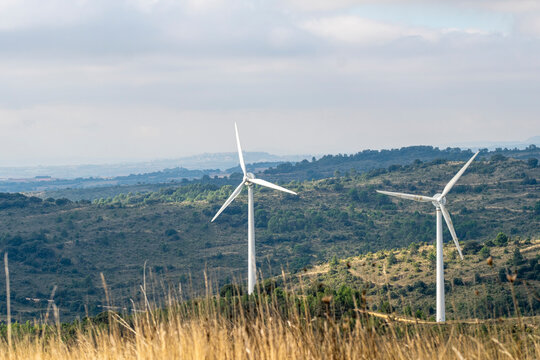 A picturesque view featuring two wind turbines surrounded by lush greenery and rolling hills, symbolizing renewable energy and sustainable development in nature in Navarra Spain